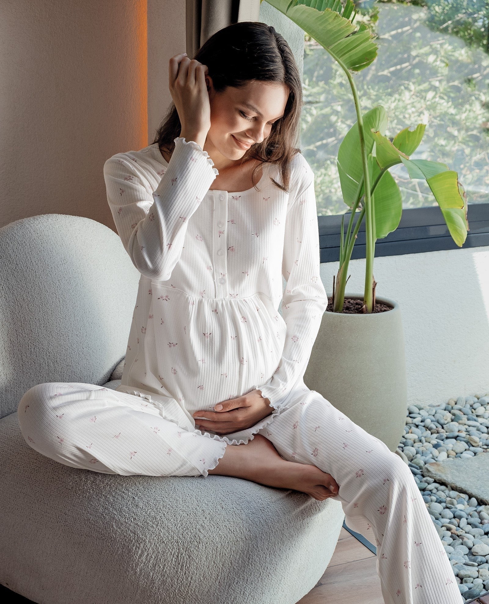 Pregnant woman in white floral maternity pajama set sitting on chair, Artış Collection