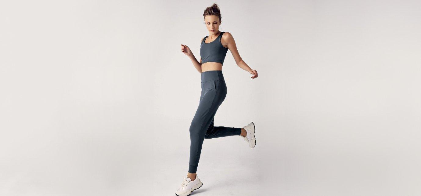 Woman in dark jogger set and sneakers posing for Artış Collection activewear