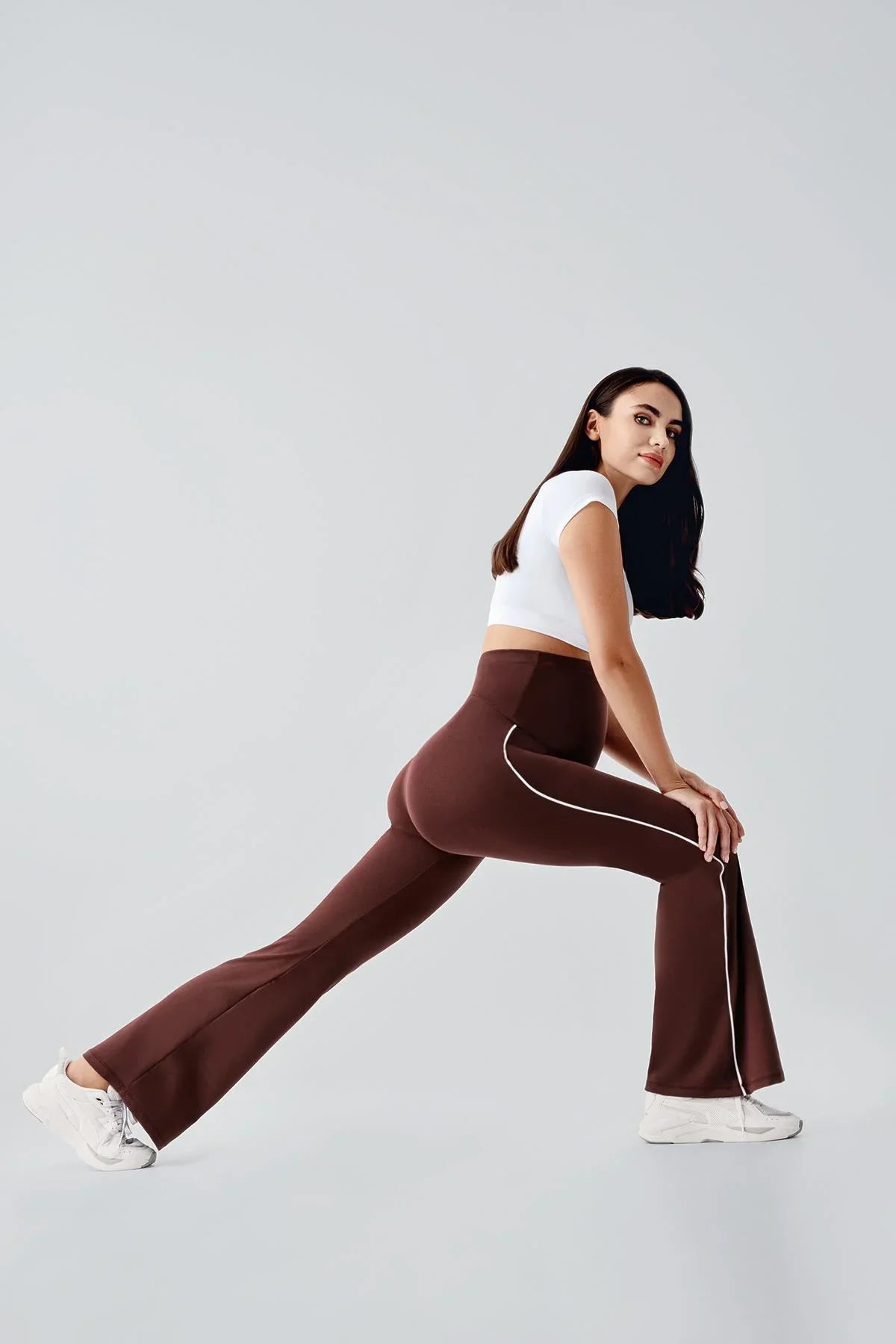 Woman modeling high-waist brown maternity flare leggings with white piping from Artış Collection