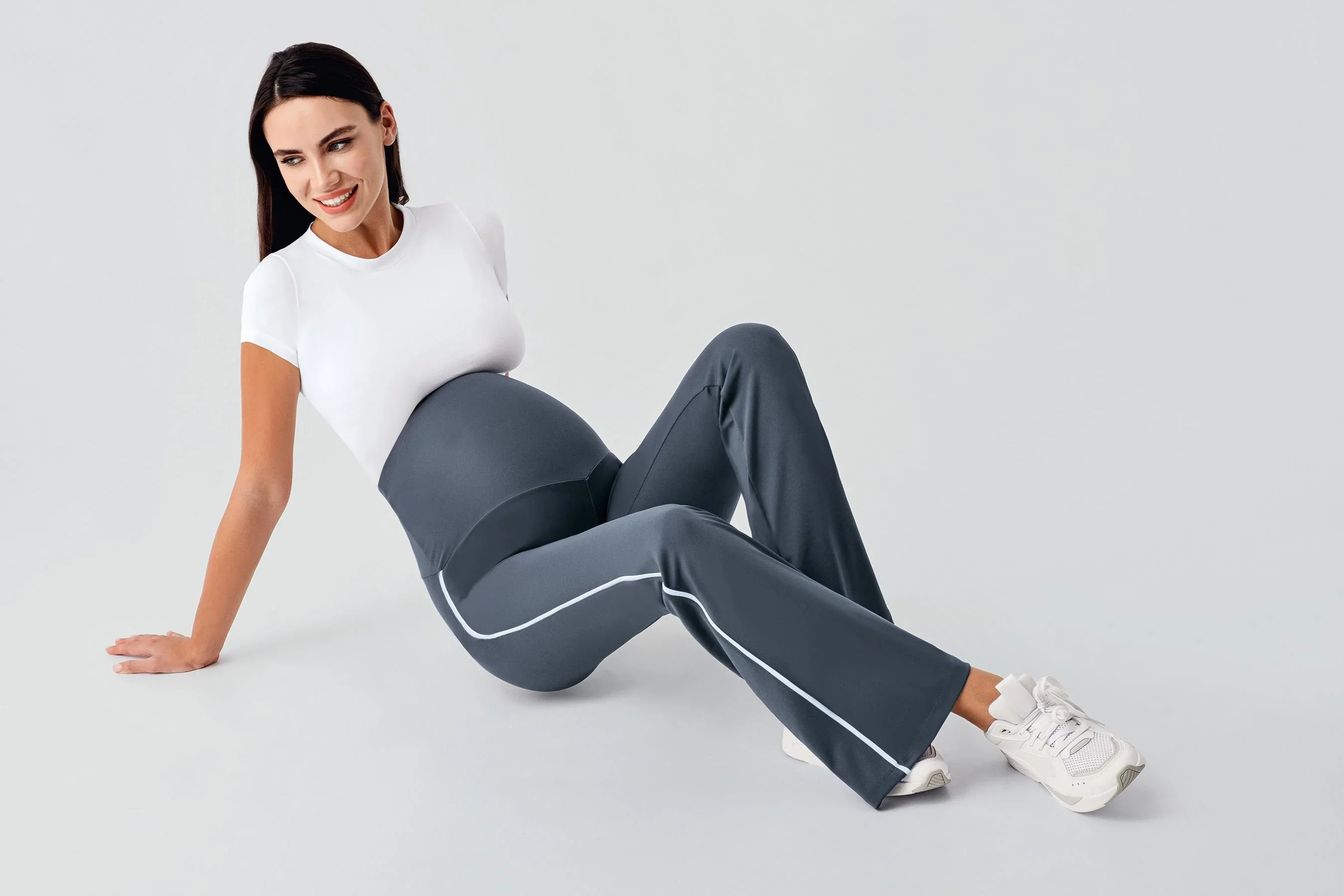 Pregnant woman in high-waisted stretchy maternity leggings and white top, Artış Collection